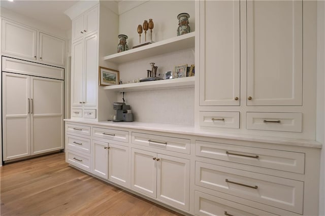 bar with white cabinets, paneled refrigerator, and light hardwood / wood-style flooring