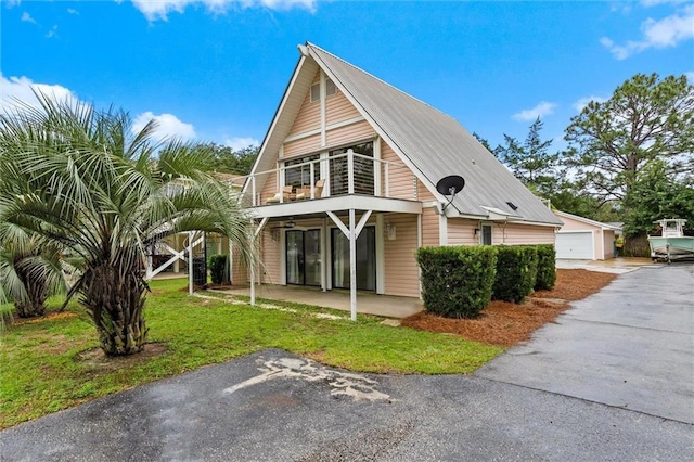 view of front of home featuring a balcony, a front yard, an outbuilding, and a garage