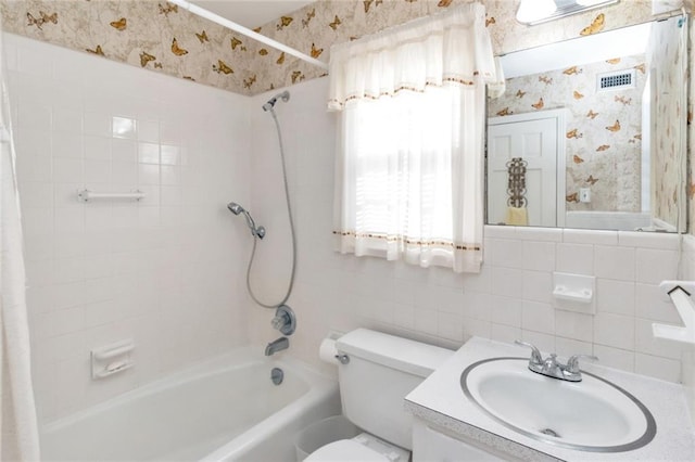 full bathroom featuring tiled shower / bath, vanity, and toilet