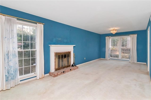 unfurnished living room featuring a brick fireplace, plenty of natural light, and carpet flooring