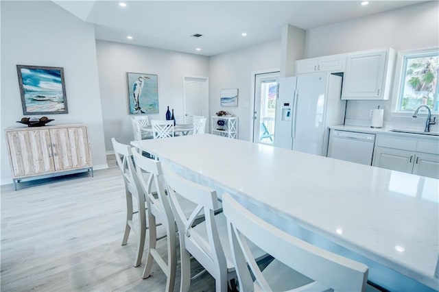 3150 State Highway 180, Gulf Shores, AL 36571 - kitchen with white appliances, light wood finished floors, light countertops, a breakfast bar area, and white cabinets