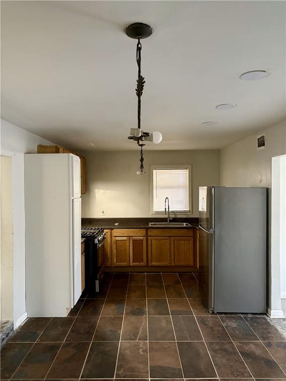 kitchen featuring pendant lighting, stainless steel appliances, sink, and dark tile patterned floors