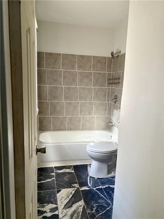 bathroom featuring tiled shower / bath combo and toilet