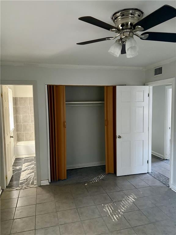 unfurnished bedroom featuring ornamental molding, light tile patterned floors, ensuite bathroom, and a closet