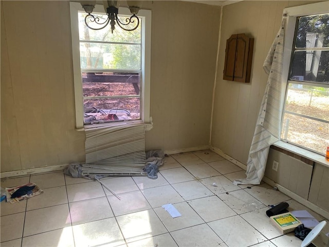 unfurnished room with a notable chandelier and light tile patterned floors