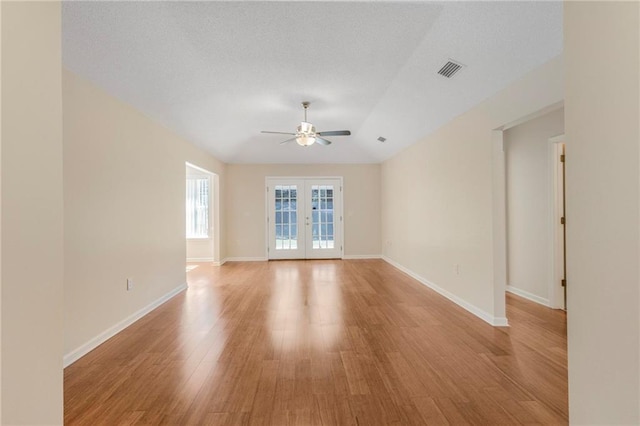 empty room with visible vents, baseboards, light wood-style flooring, ceiling fan, and french doors