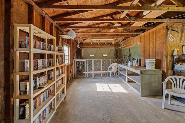 interior space featuring concrete flooring, wooden walls, and vaulted ceiling