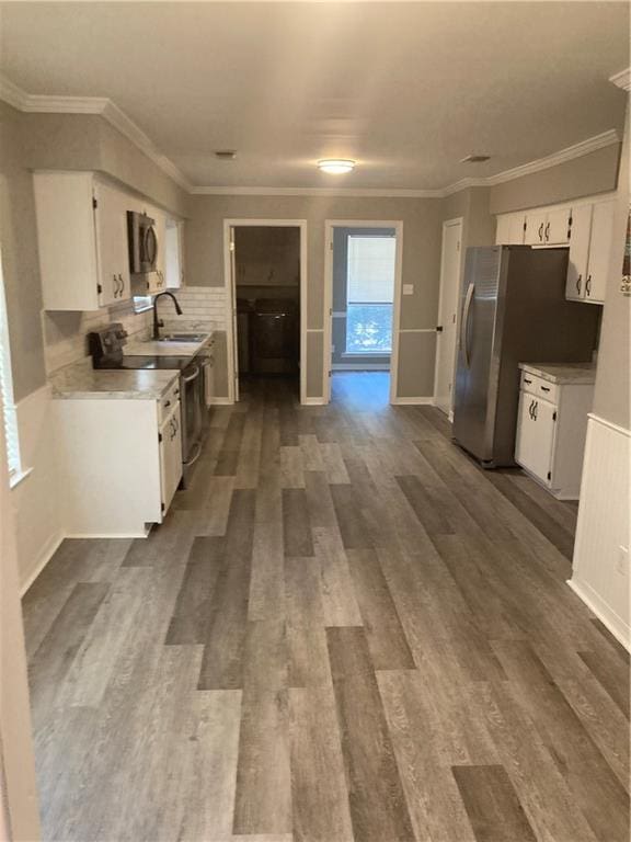 kitchen featuring hardwood / wood-style flooring, stainless steel appliances, backsplash, sink, and white cabinets