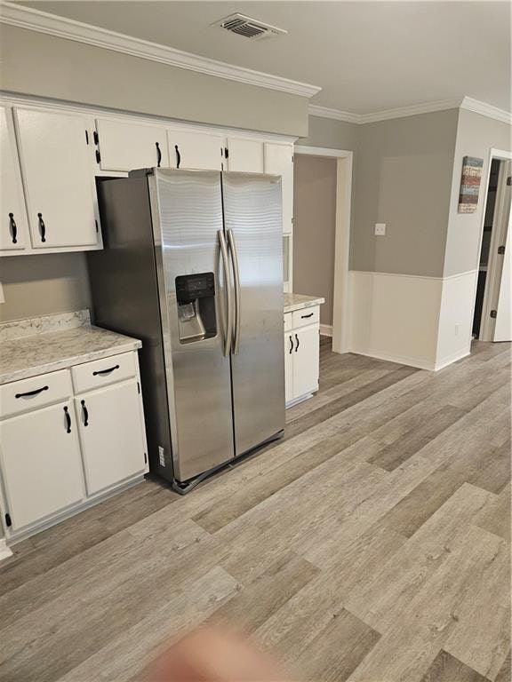 kitchen featuring white cabinetry, light hardwood / wood-style floors, crown molding, and stainless steel refrigerator with ice dispenser