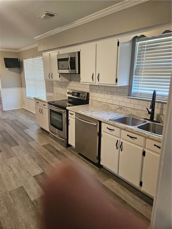 kitchen with sink, white cabinetry, stainless steel appliances, and light wood-type flooring