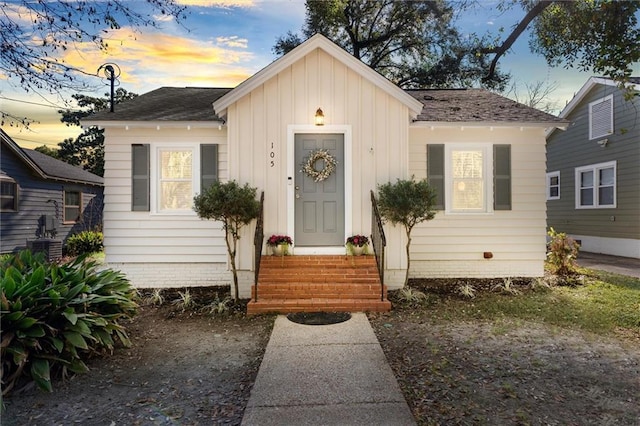 view of front facade featuring entry steps, board and batten siding, and roof with shingles