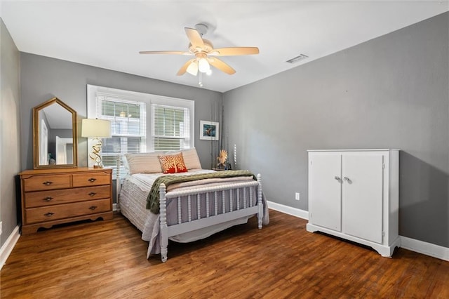 bedroom with ceiling fan, visible vents, baseboards, and wood finished floors