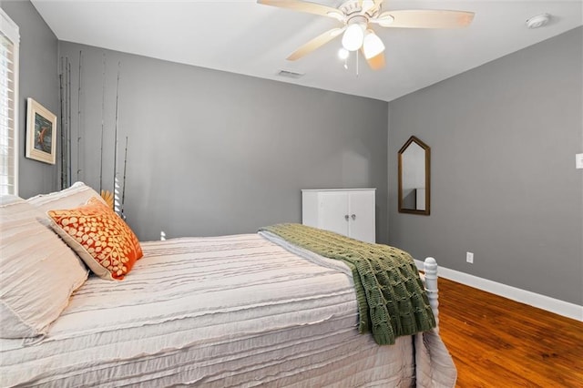 bedroom featuring visible vents, ceiling fan, baseboards, and wood finished floors