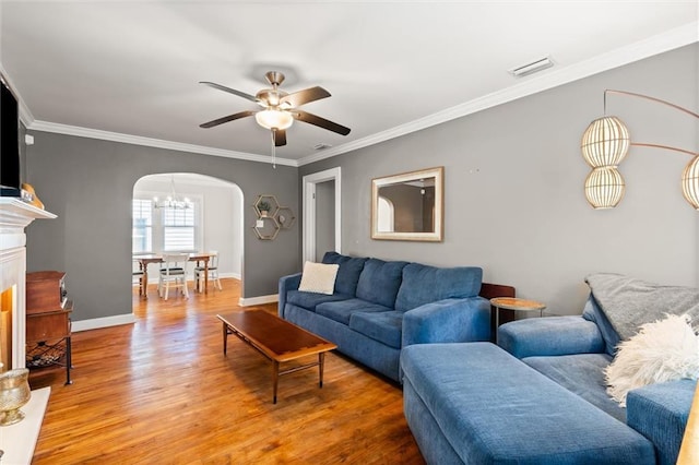 living room featuring visible vents, arched walkways, ornamental molding, and light wood finished floors