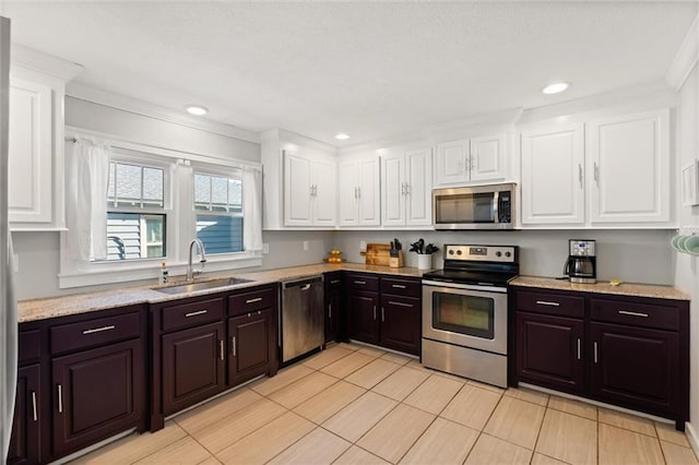 kitchen featuring dark brown cabinets, white cabinets, stainless steel appliances, and a sink