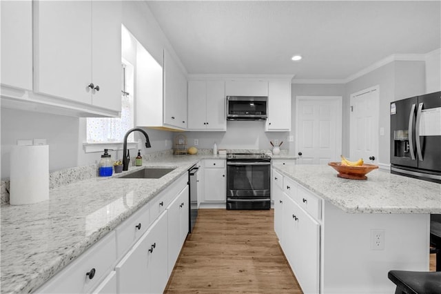 kitchen with appliances with stainless steel finishes, a sink, white cabinets, crown molding, and light wood finished floors