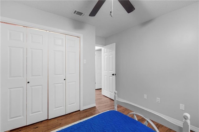 bedroom with wood finished floors, a closet, baseboards, ceiling fan, and a textured ceiling