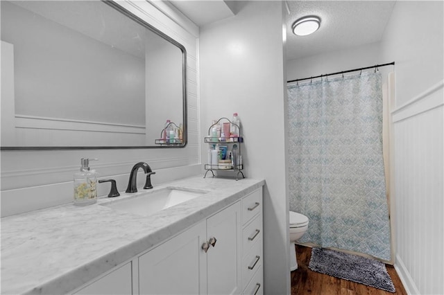 bathroom with wood finished floors, toilet, vanity, and curtained shower