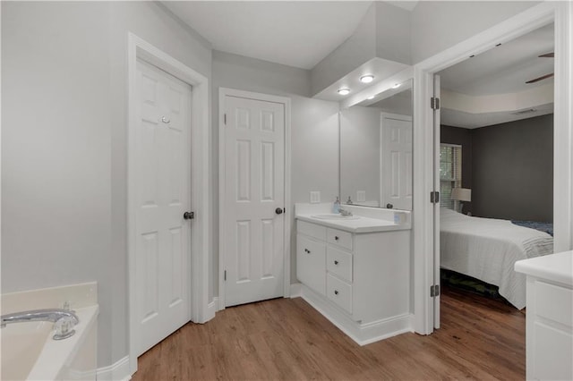 bathroom featuring wood finished floors, connected bathroom, a garden tub, and vanity