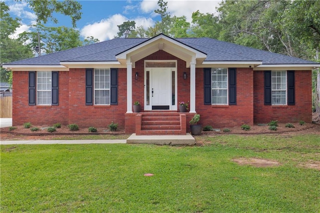 ranch-style house with brick siding, a front lawn, and roof with shingles