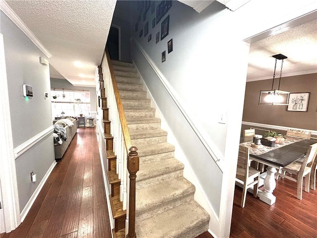 stairway featuring ornamental molding, wood-type flooring, and a textured ceiling