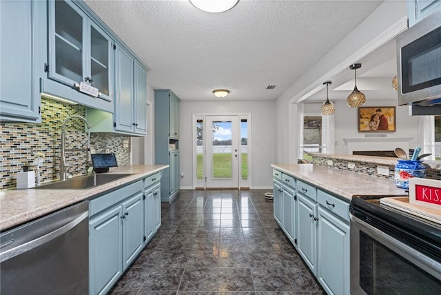 kitchen with light countertops, appliances with stainless steel finishes, a sink, and glass insert cabinets