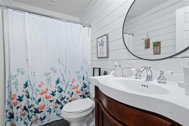 bathroom with a textured ceiling, curtained shower, toilet, wooden walls, and vanity