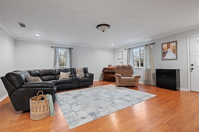 living area featuring baseboards, visible vents, wood finished floors, and ornamental molding