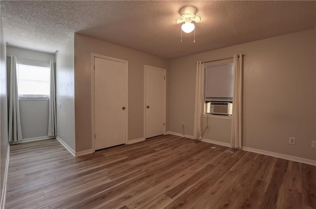 unfurnished bedroom featuring a textured ceiling, hardwood / wood-style floors, and cooling unit