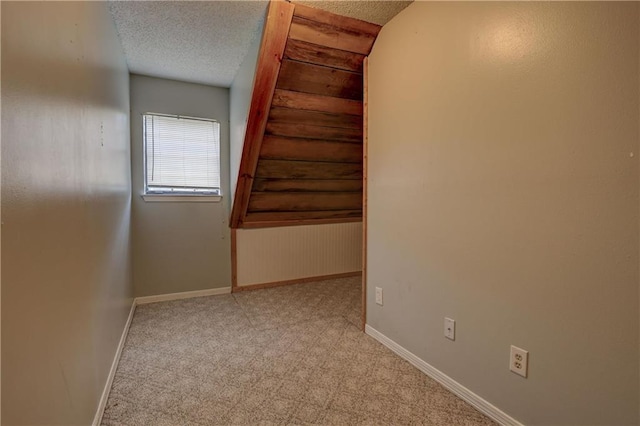 unfurnished room featuring a textured ceiling and light colored carpet