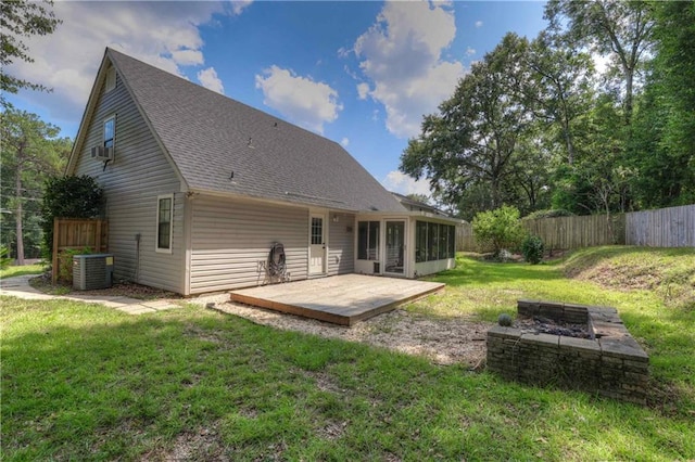 back of property with central AC and a lawn