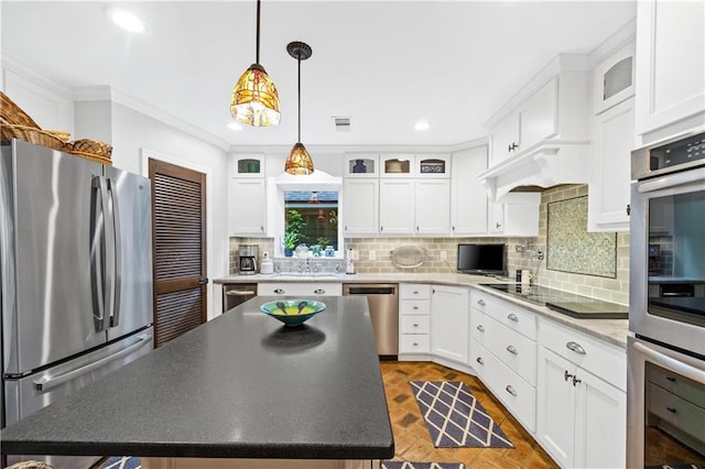 kitchen featuring white cabinets, a kitchen island, stainless steel appliances, crown molding, and decorative light fixtures