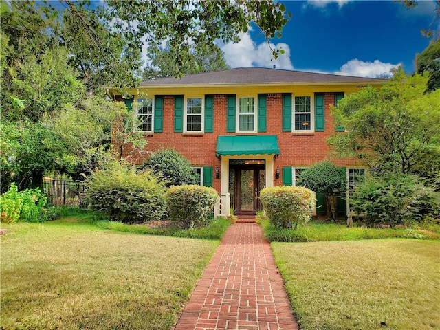 view of front facade featuring brick siding, a front yard, and fence