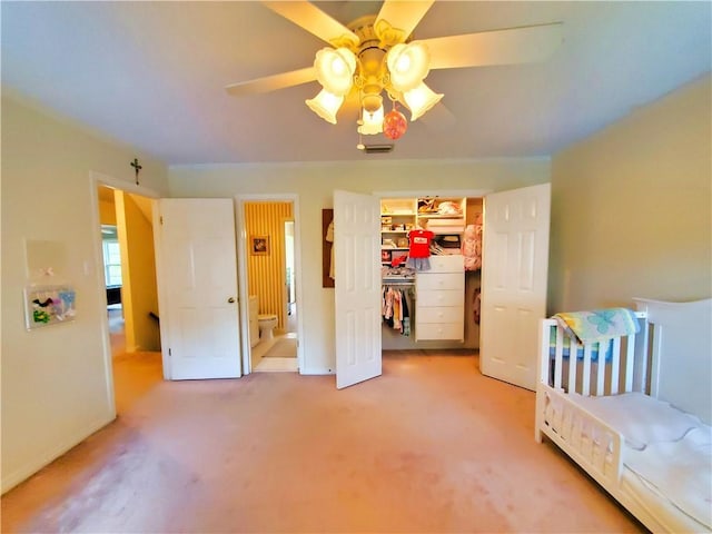 bedroom featuring a walk in closet, a ceiling fan, connected bathroom, a closet, and carpet