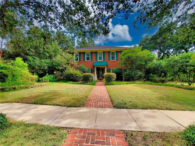 colonial home featuring brick siding and a front yard