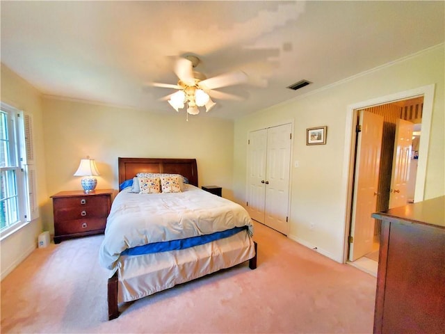 bedroom featuring a ceiling fan, visible vents, ornamental molding, a closet, and light carpet