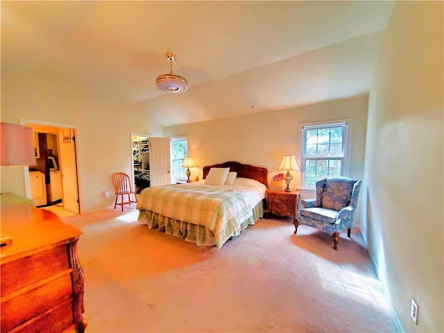 bedroom featuring a walk in closet, lofted ceiling, washer / clothes dryer, baseboards, and light colored carpet