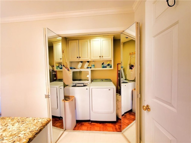 washroom featuring washer and clothes dryer, cabinet space, and ornamental molding