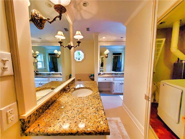 bathroom with washer and dryer, vanity, a chandelier, and ornamental molding