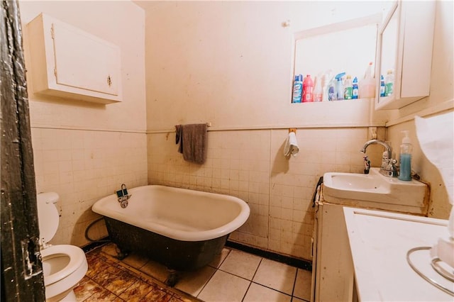 bathroom with a wainscoted wall, toilet, tile patterned flooring, a freestanding bath, and vanity