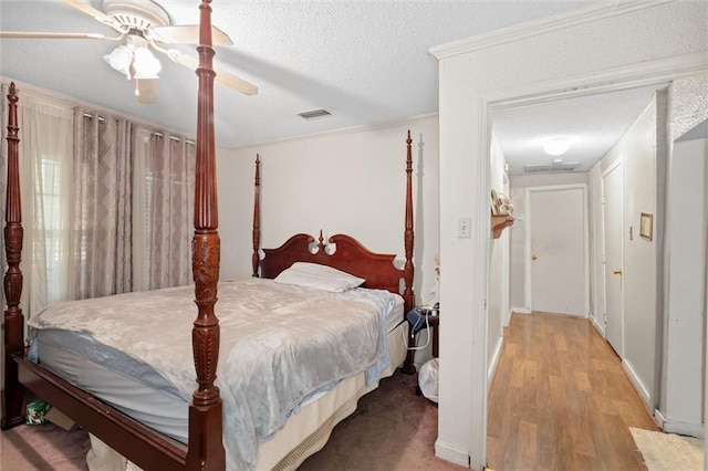 bedroom with ceiling fan, light hardwood / wood-style floors, and a textured ceiling