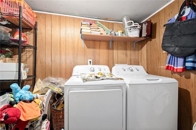 laundry room with washing machine and clothes dryer and wood walls