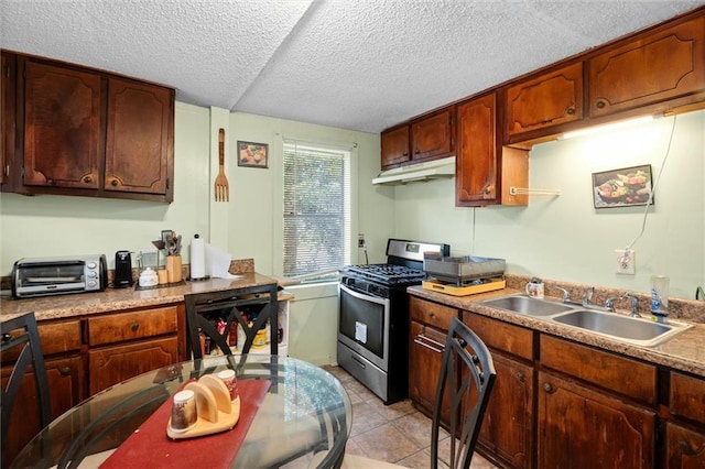 kitchen featuring a textured ceiling, sink, light tile patterned floors, and stainless steel appliances