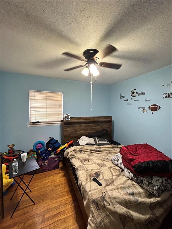 bedroom featuring hardwood / wood-style floors, ceiling fan, and a textured ceiling