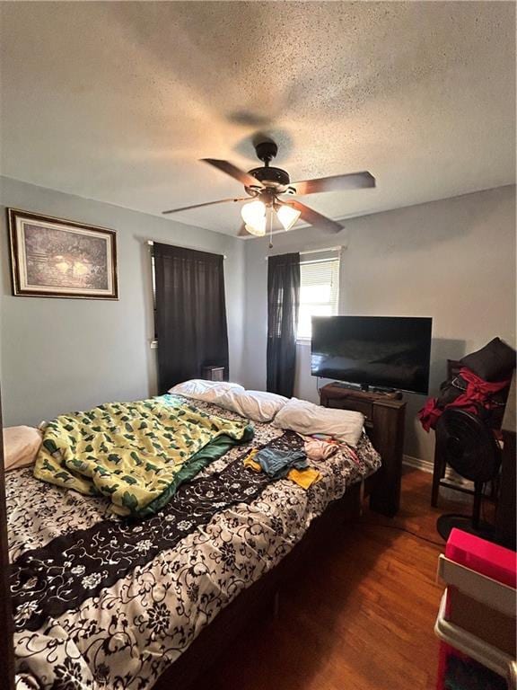 bedroom featuring a textured ceiling, ceiling fan, and dark wood-type flooring