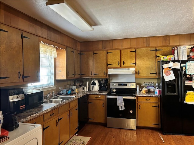 kitchen featuring black appliances, sink, dark hardwood / wood-style floors, a textured ceiling, and washer / dryer