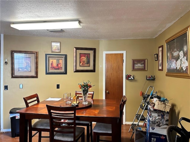 dining area featuring wood-type flooring and a textured ceiling