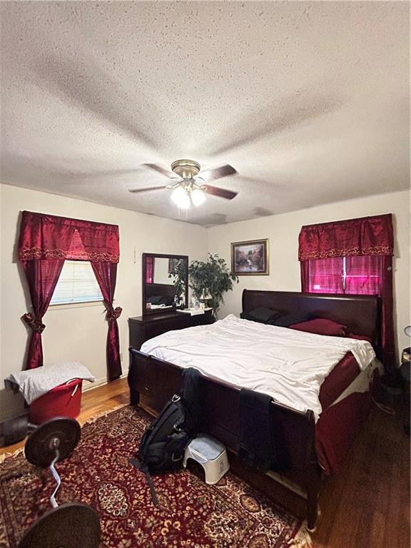 bedroom with hardwood / wood-style flooring, ceiling fan, and a textured ceiling