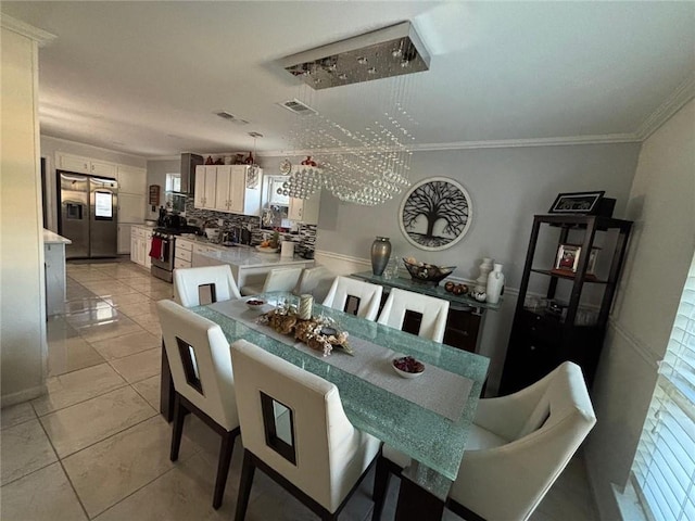 dining space with light tile patterned floors, a notable chandelier, and ornamental molding