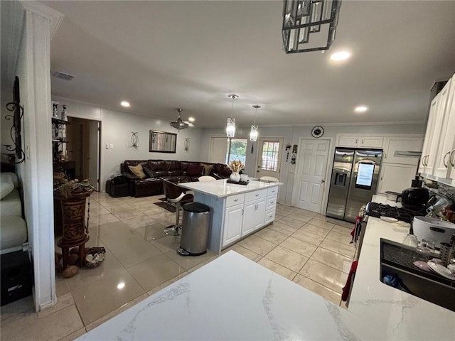 kitchen with white cabinetry, a center island, stainless steel refrigerator with ice dispenser, decorative light fixtures, and a kitchen bar